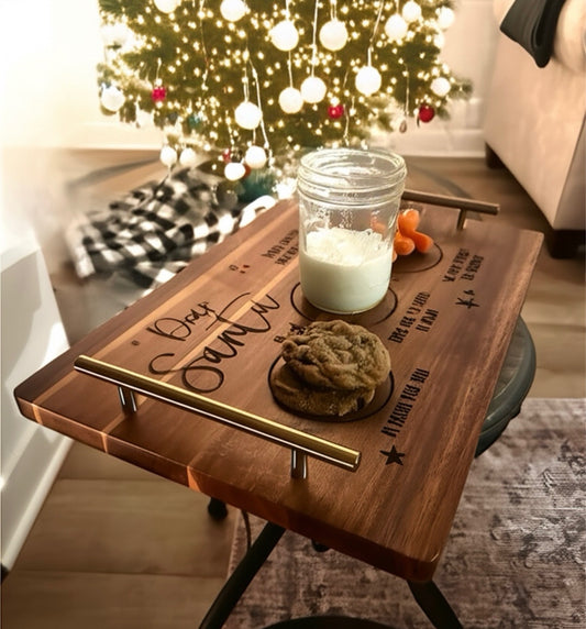 Wooden tray with cookies and a glass of milk, placed on a surface with a Christmas tree in the background.