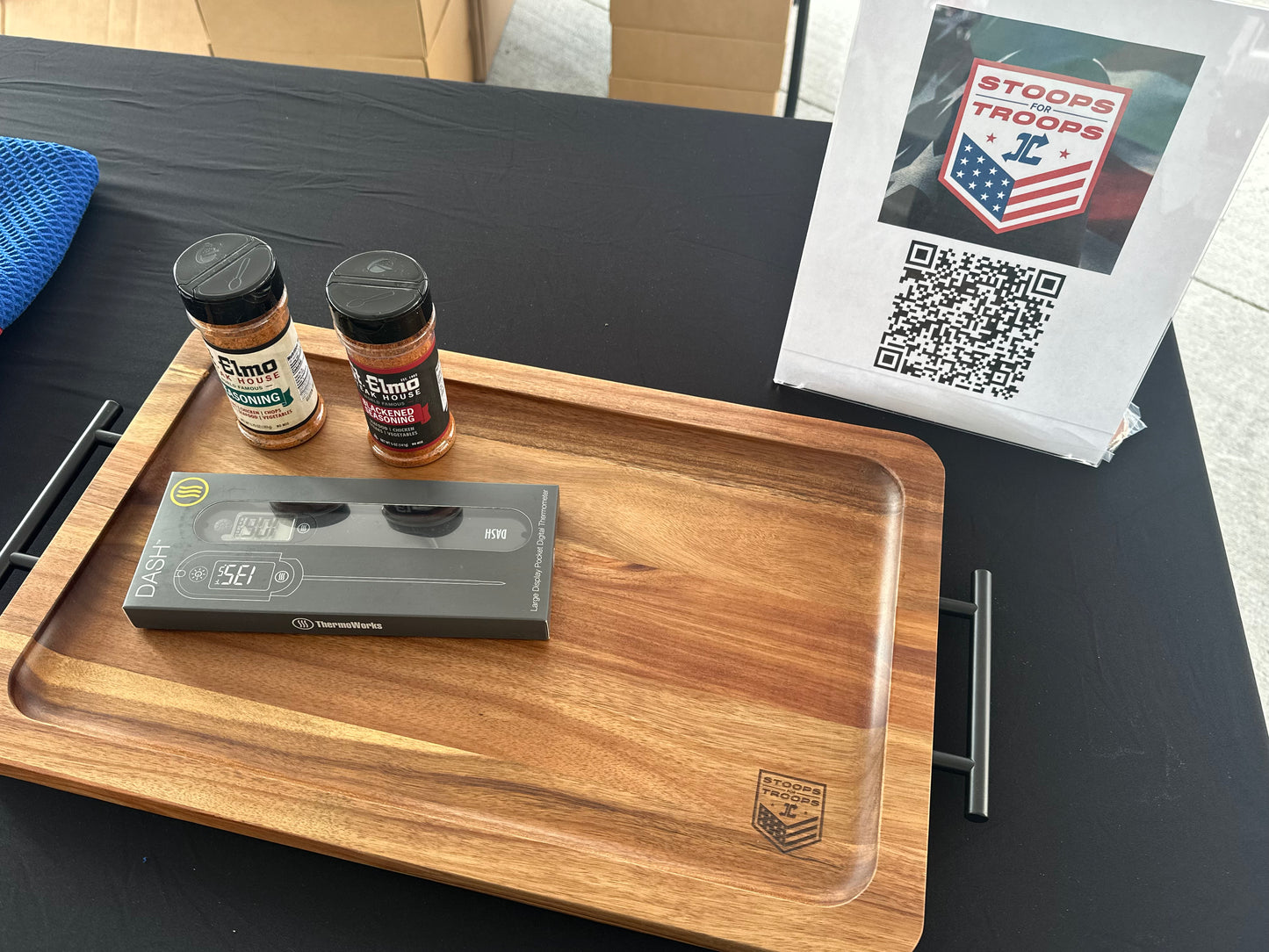 Wooden tray with items including a VHS player, two jars, and a paper with a QR code on a black surface.