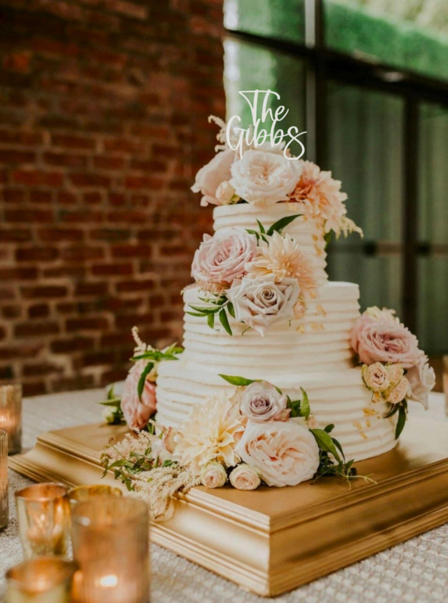 A wedding cake with a white frosting topper ' on top, decorated with a floral arrangement and berries.