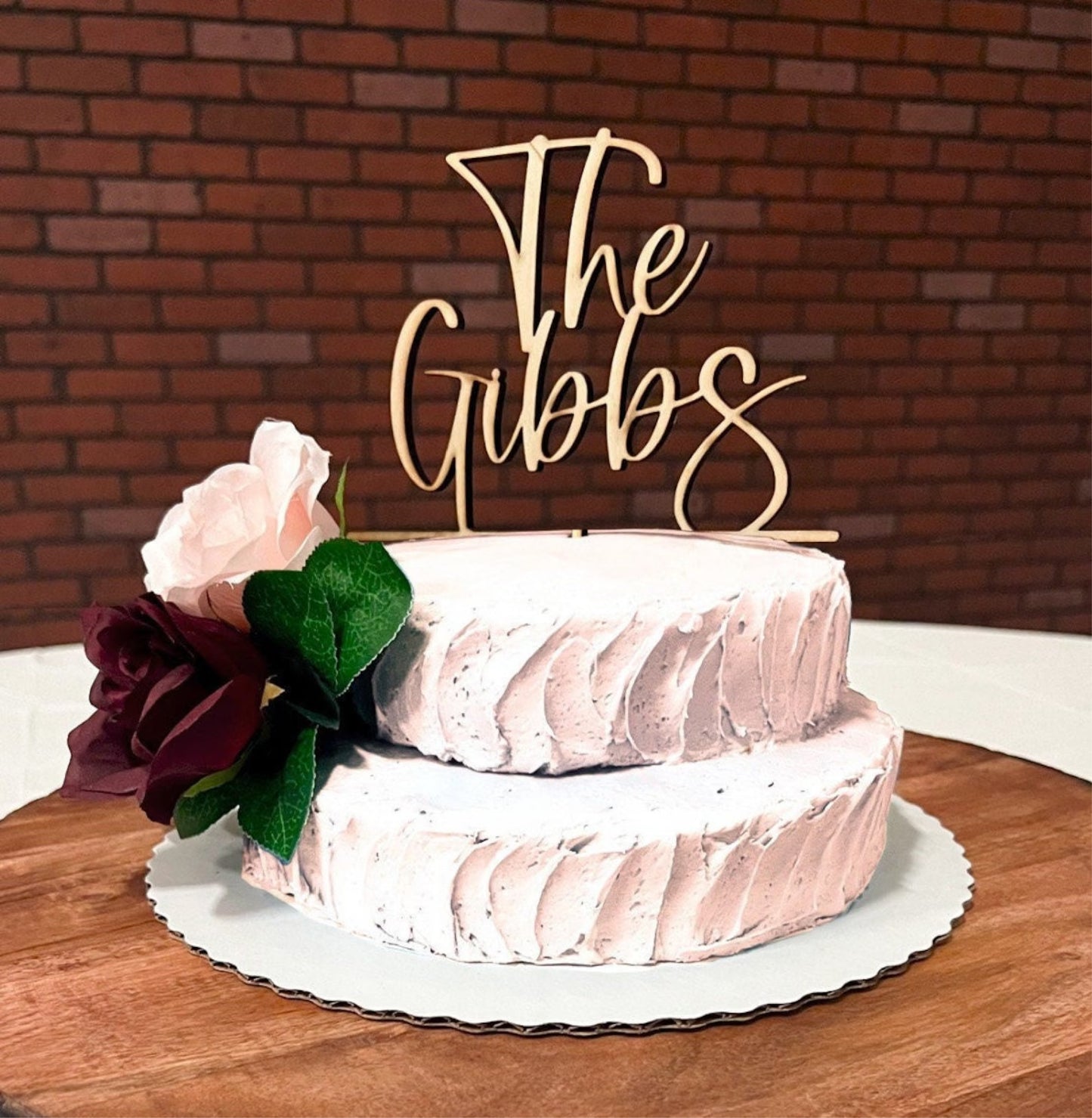 A wedding cake with a white frosting topper  on top, decorated with a floral arrangement and berries.