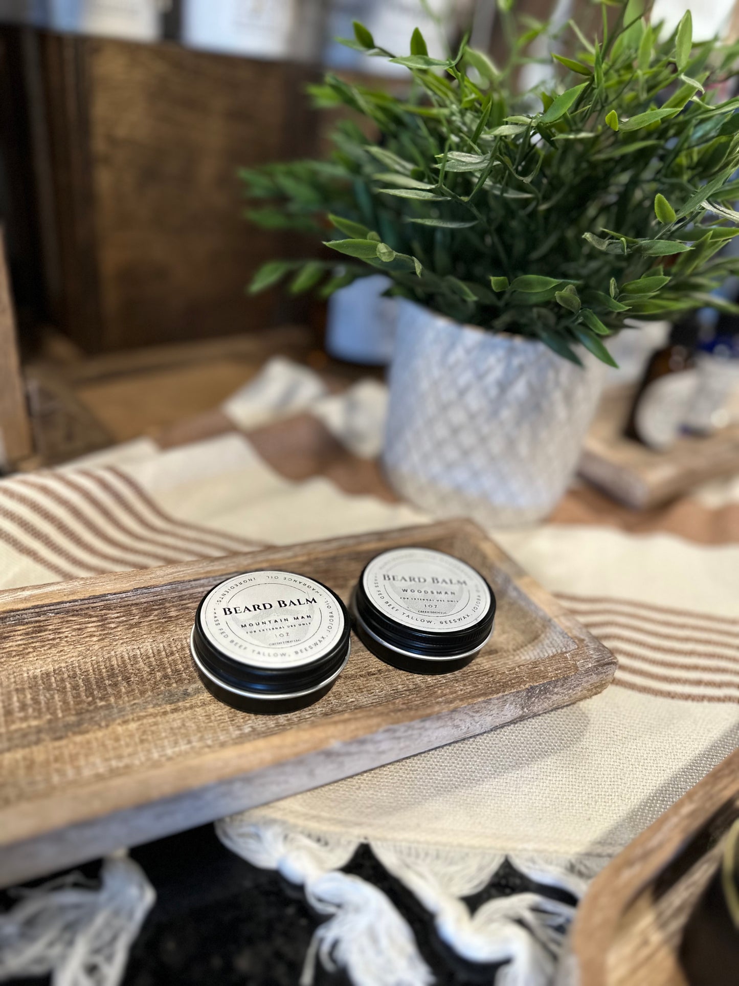 Far away picture of two Green Eden Beard Balms on wooden tray