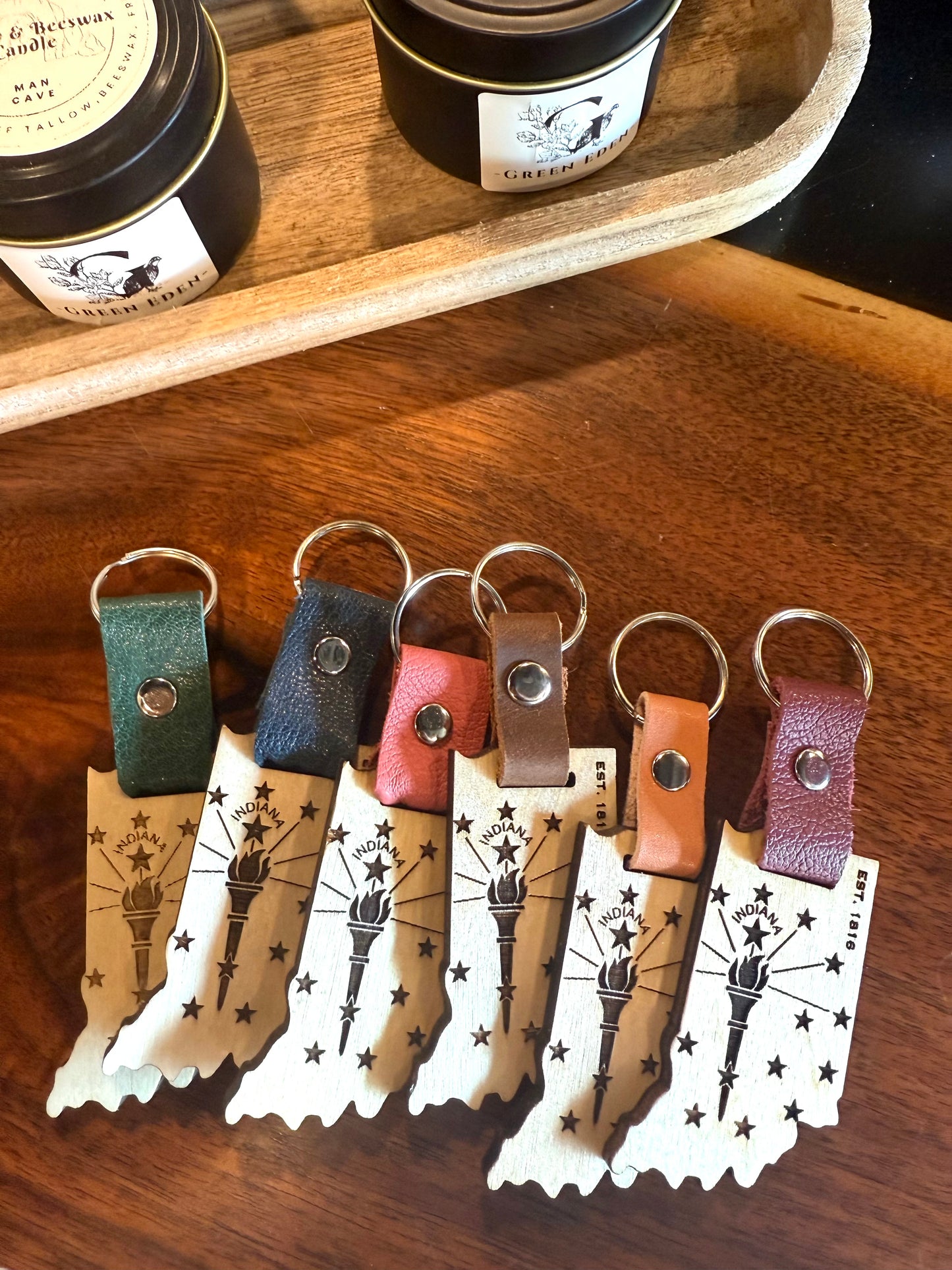 Set of leather keychains on a wooden surface with branded labels.