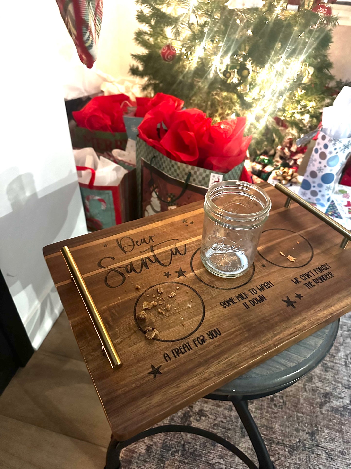 Wooden tray with engraved text and a glass jar on a table with a blurred background