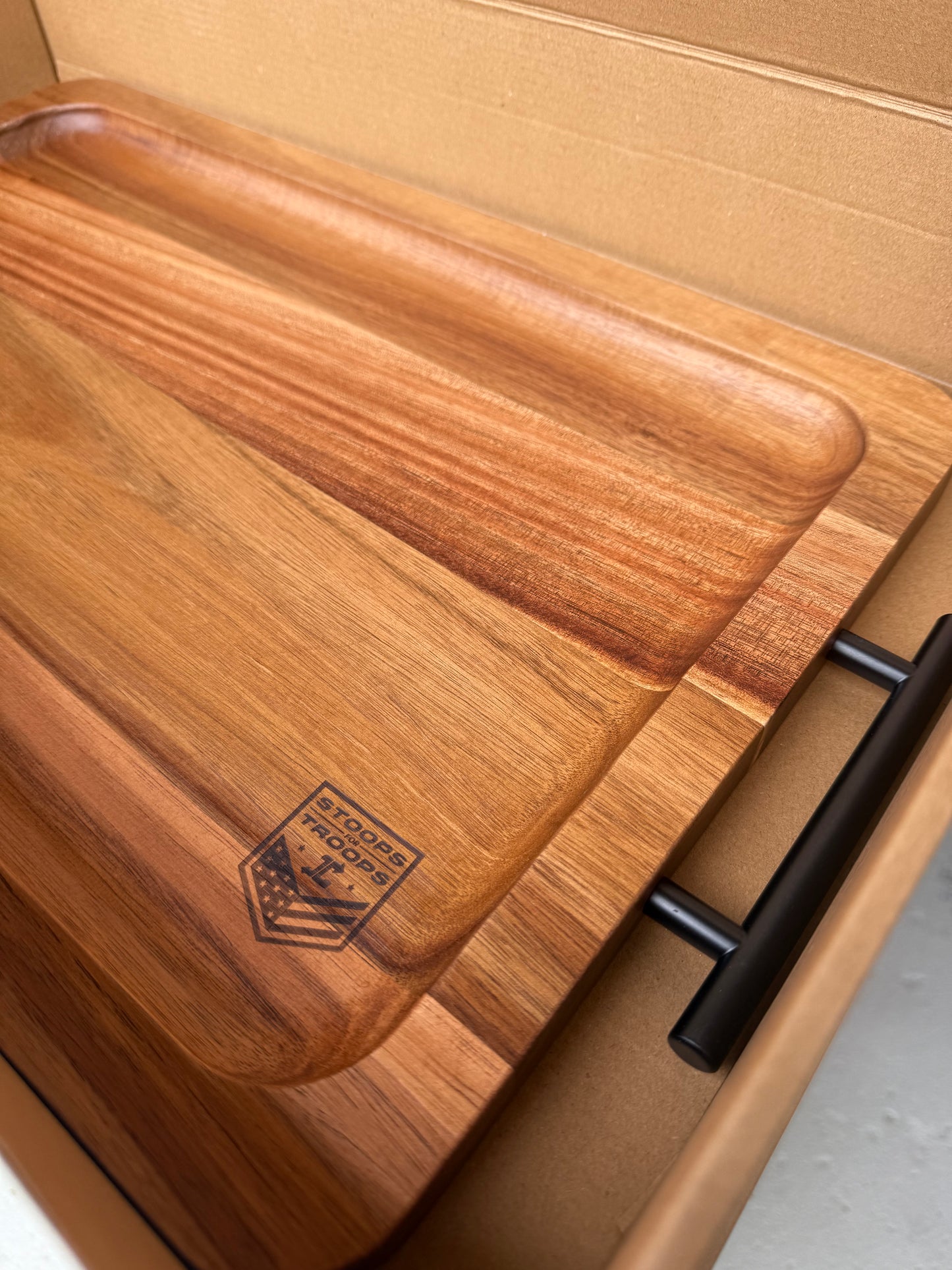 Wooden cutting board with a black handle on a cardboard background