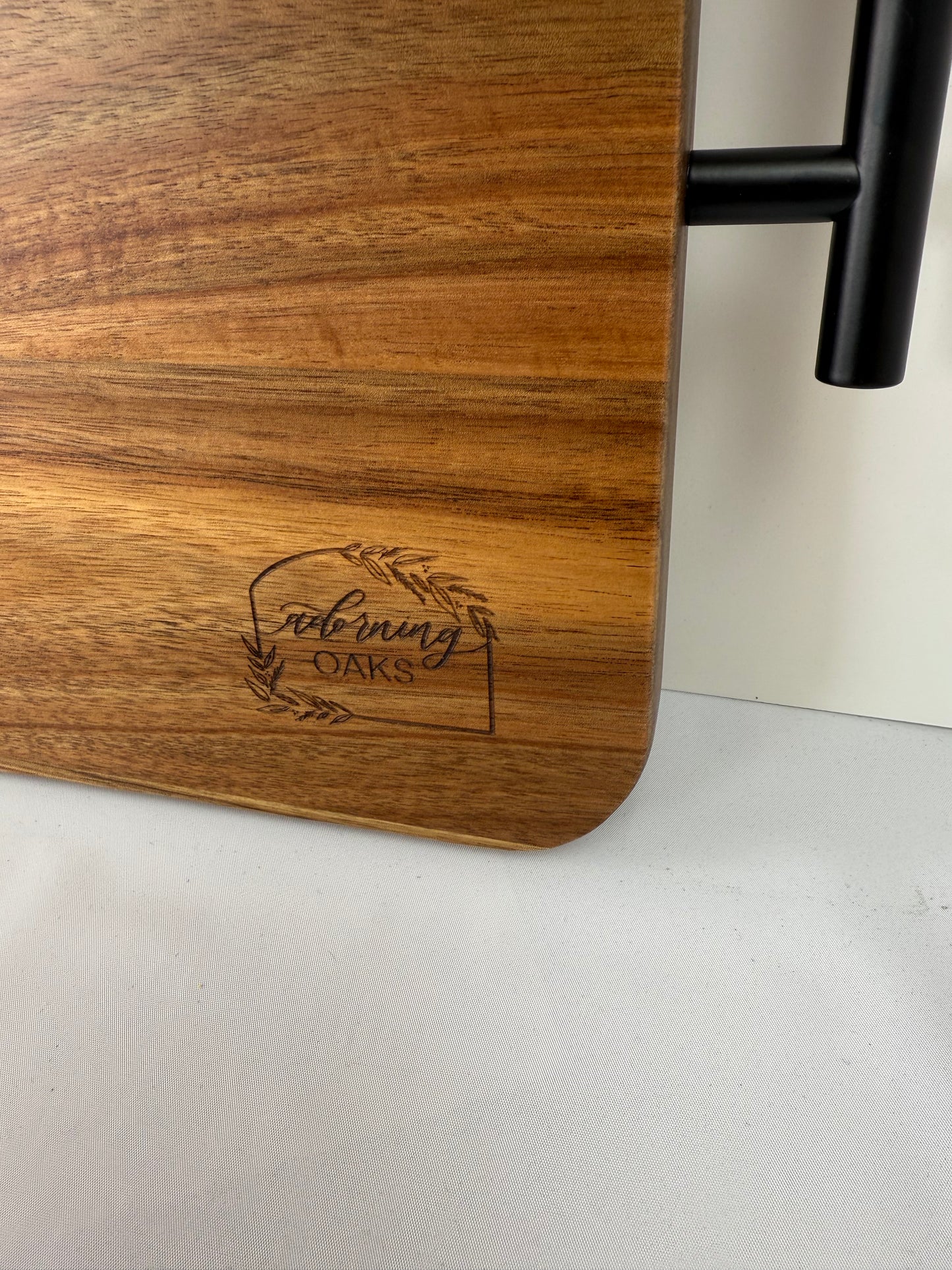 Wooden cutting board with engraved logo on a white surface