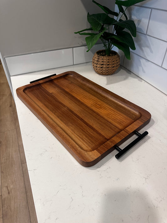 Wooden cutting board with black handles on a white surface