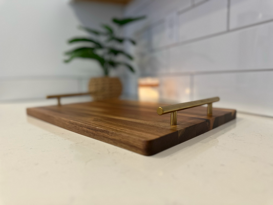 Wooden tray with brass handles on a light surface, blurred background