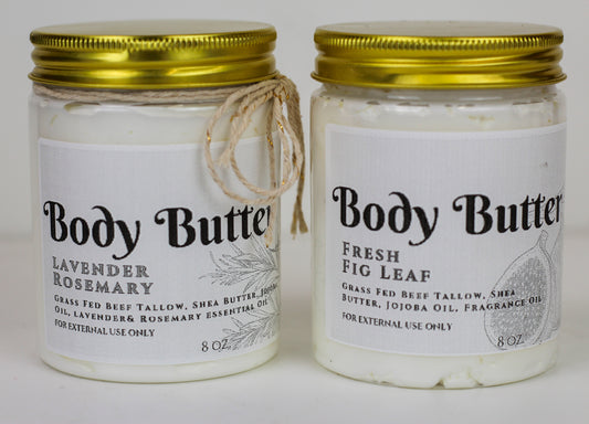 Two jars of Green Eden Body Butter, one labeled Lavender Rosemary and the other labeled Fresh Fig Leaf, with a rope handle on the lid of each jar.