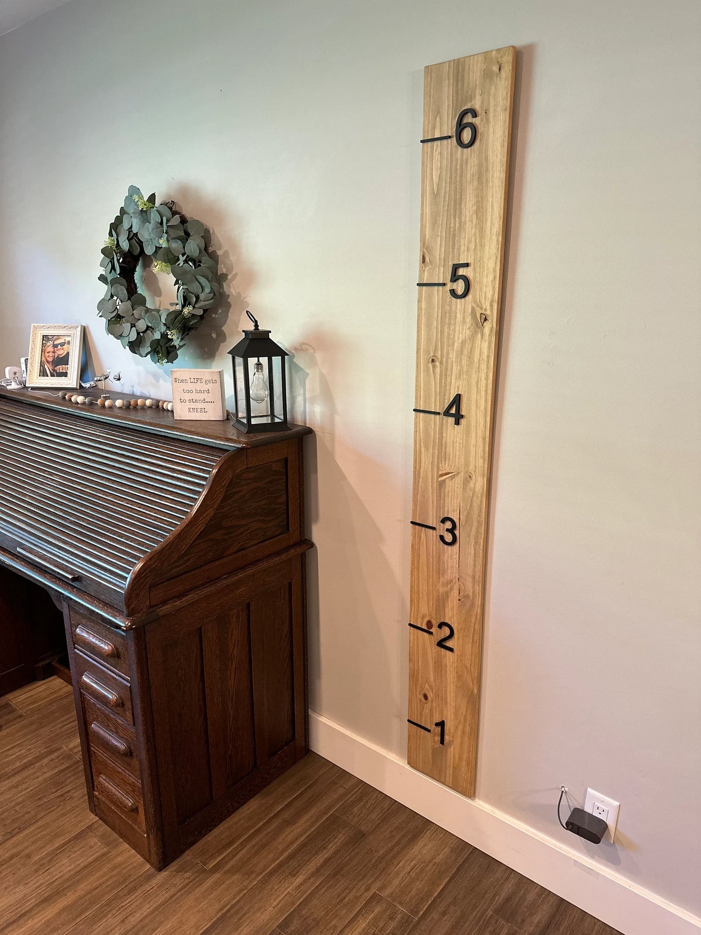 A wooden growth chart with 3D cutout numbers and black painted numbers.