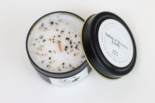 A clear candle with a wooden wick, embedded in a black jar with a lid that has 'Green Eden' branding on it. The candle is visibly fragrant with a warm, earthy scent.