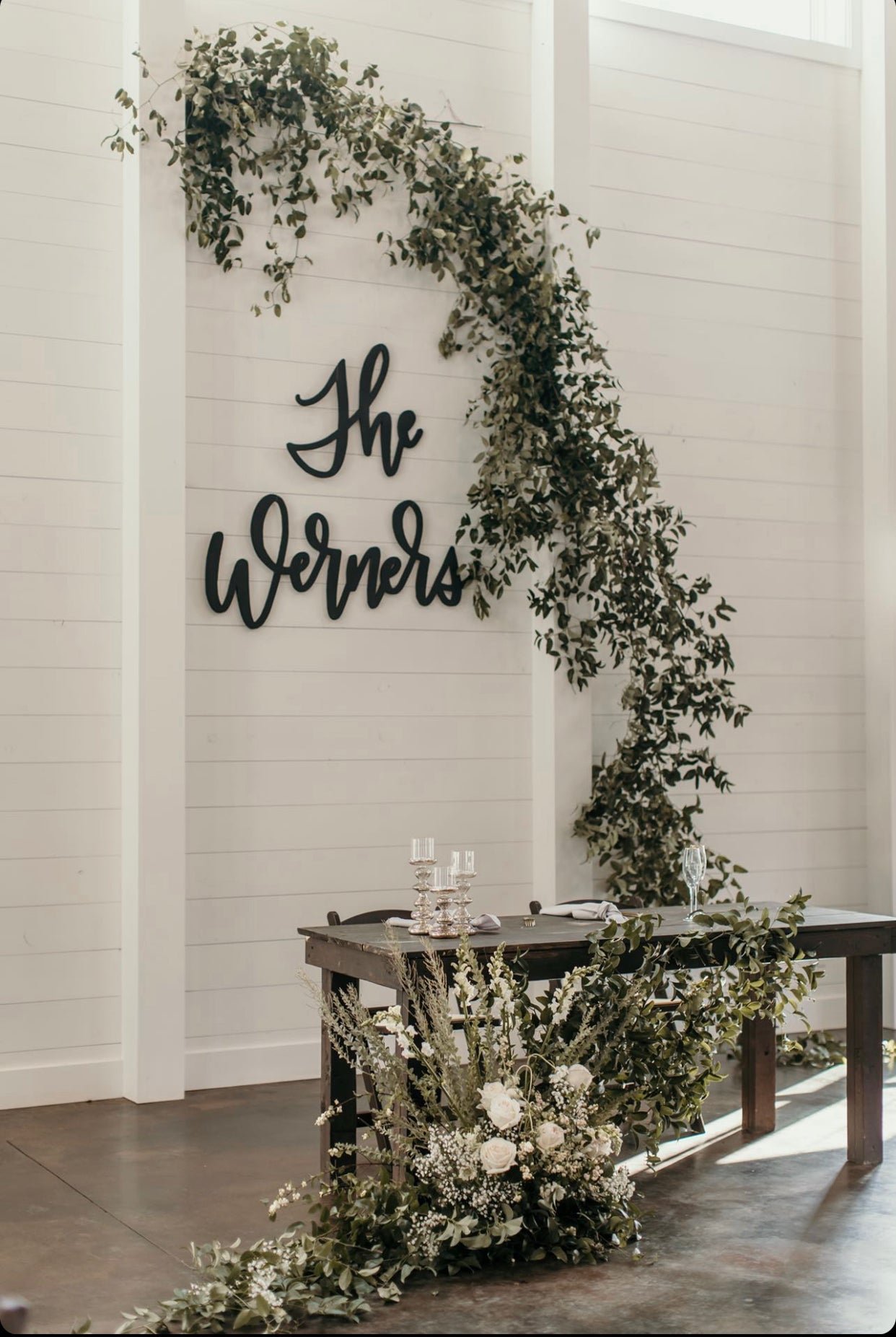 A wooden cutout with the word 'The Werners' in a large, bold font, mounted at wedding