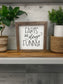 Framed sign with 'Farts are always funny' text on a wooden shelf with plants.