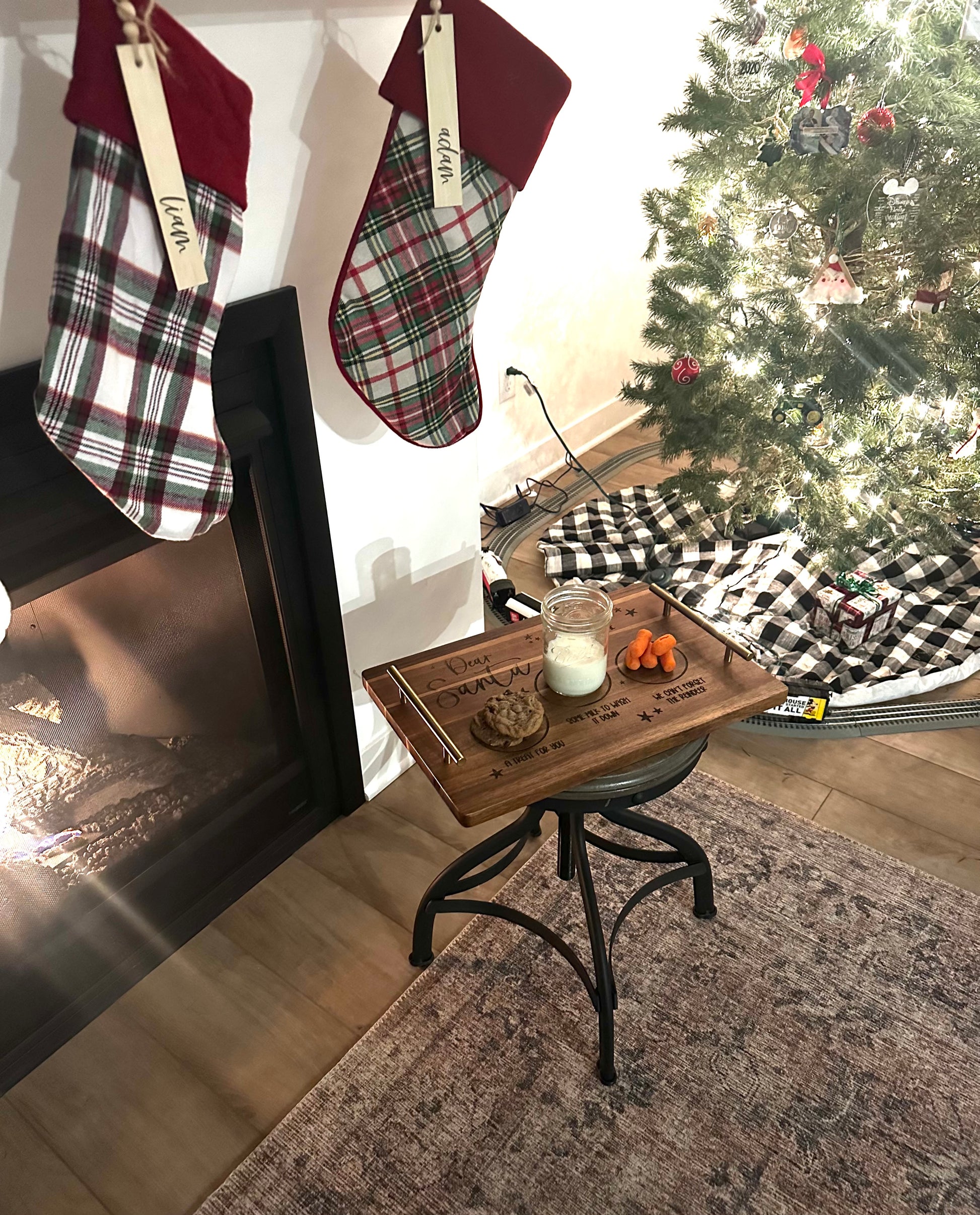 Christmas stockings hanging by a fireplace with a decorated tree in the background.