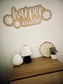 Decorative wall sign with 'harper marie' on a wall above a wooden dresser with decorative items.