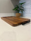 Wooden cutting board with a black handle on a kitchen counter